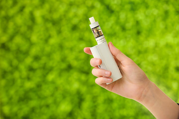 Female hand with modern vape mod outdoors