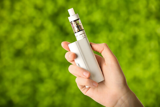 Female hand with modern vape mod outdoors, closeup