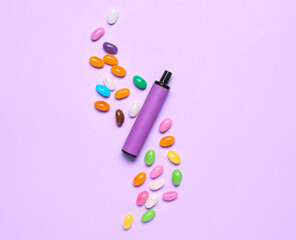 Disposable electronic cigarette and candies on purple background
