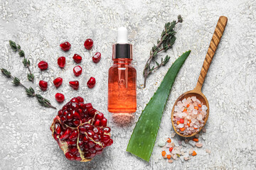 Bottle of natural serum, spoon with sea salt, aloe leaf, pomegranate and thyme on grunge background