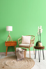 Wicker chair and tables near green wall in room