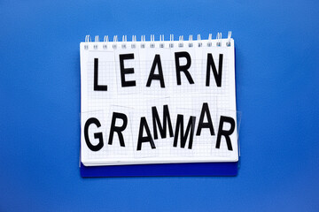 Notebook with text LEARN GRAMMAR on blue background