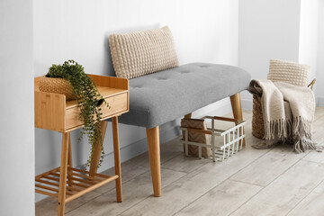 Soft bench with baskets and table near light wall