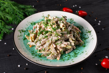meat salad with vegetables and mayonnaise on a black wooden background