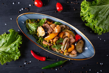 fried meat with vegetables. on a black wooden background