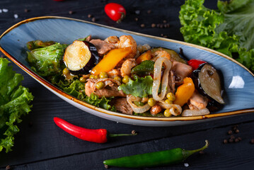 fried meat with vegetables. on a black wooden background