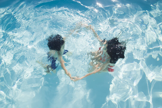 art portrait of girl and boy swimming underwater in the pool in summer