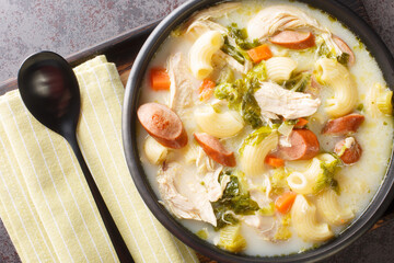 Creamy Chicken Sopas is a Filipino soup with pasta, vegetables, sausages and chicken close-up in a...