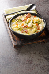 Filipino Chicken Macaroni Soup with vegetables, chicken and elbow pasta close-up on a plate on the table. Vertical