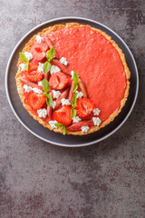 Mousse tart with strawberries, rhubarb, mint and whipped cream close-up on the table. Vertical top view from above