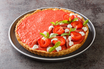 Festive tart with strawberry and rhubarb mousse, mint and whipped cream close-up on a plate on the table. Horizontal