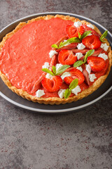 Mousse tart with strawberries, rhubarb, mint and whipped cream close-up on the table. Vertical