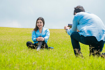 Fototapeta premium A guy taking a picture of a girl in the field, Boyfriend taking a picture of his girlfriend in the field, Two friends taking photos with the cell phone in the field