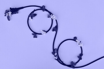 Very pery the color of the year 2022 A black wire from household appliances lies on a beige background in the form of a percentage sign. The concept of discounts on household appliances and electrifyi