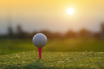 Golf ball on tee in beautiful golf course at sunset background.