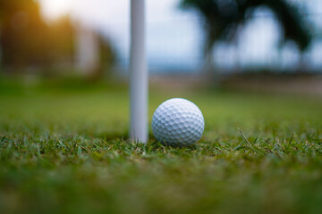 Top view of a golf ball on green course at hole.