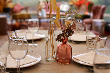 Glass bottles with dry branches in festive table setting