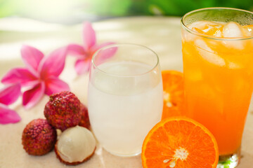 Glass Orange Juice And Lychee Juice On Sand Background. Summer Refreshing Drinks. 