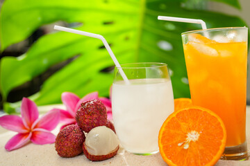 Glass Orange Juice And Lychee Juice On Sand Background. Summer Refreshing Drinks. 
