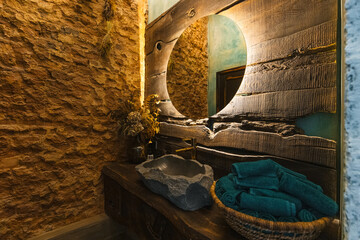 Design of bathroom interior with unprocessed stones and wood