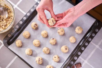 Woman holding ball of raw dough while making Chocolate chip cookies