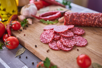 Sliced salami sausage on wooden cutting board at domestic kitchen