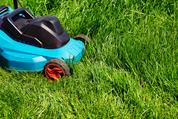 Electric lawnmower machine trimming green grass. Lawn cutting summer time