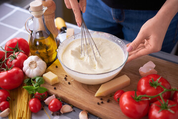 making homemade pasta carbonara - parmesan and cream sauce in a glass bowl
