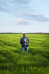 Naklejka na ściany i meble Portrait of senior farmer standing in barley field.