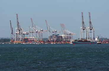 Southampton, England, UK. 2022. View of cranes and shipping at DP World container terminal and a small container ship the BF Fortaleza departing. Southampton Water, UK.