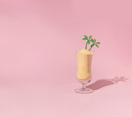 Summer tropical creative layout with cockatil glass with sand and palm trees figurines on pastel pink background. 80s, 90s retro fashion aesthetic summer concept. Minimal pop art drink concept.