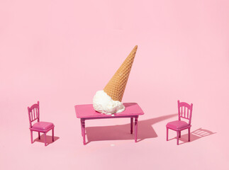 Summer creative layout with ice cream cone upside down on table with pink chairs on pastel pink...