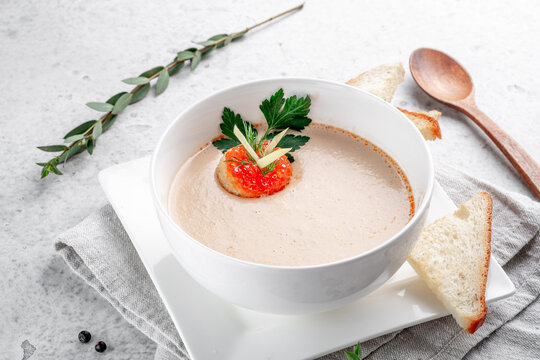 Fish cream soup with salmon in a white bowl decorated with crackers with red caviar