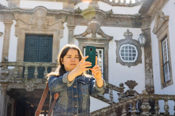 Woman taking pictures with her smartphone while standing at Mateus Palace in Vila Real, Portugal.