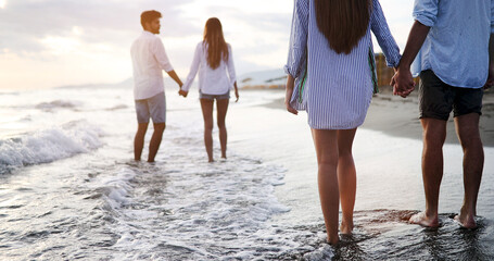 Friends having fun on the beach under sunset sunlight.