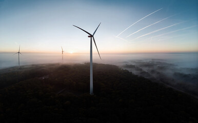 Windmills in aerial drone view in frosty morning with dusk in valleys