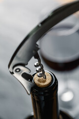 Stainless  wine corkscrew in a cork of wine bottle neck on a black rocky slate background