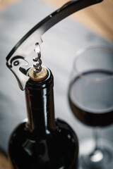 Stainless  wine corkscrew in a cork of wine bottle neck on a black rocky slate background - 508189529