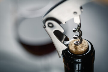 Stainless  wine corkscrew in a cork of wine bottle neck on a black rocky slate background