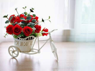Artificial red rose flowers in bike toy on table ,Bicycle with candle and white embroidered cloth for festive background or wallpaper copy space for lettering ,Valentine's day romantic love card 