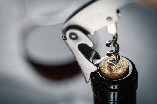 Stainless wine corkscrew in a cork of wine bottle neck on a black rocky slate background