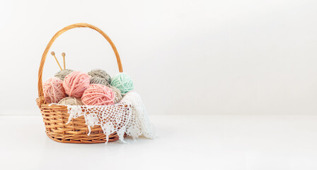 Fototapeta na wymiar Basket with balls of thread and knitting needles on a white background with copy space. Crochet, knitting as a hobby.