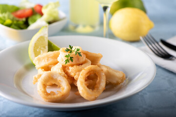 Traditional Italian fried calamari and lemon slice served on a white plate