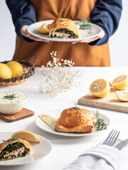 A chef serving Salmon en Croute on a white table