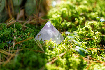 occult science and supernatural concept - close up of quartz crystal pyramid on moss in forest