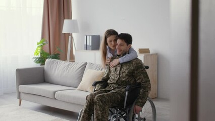 Family love and support. Young loving wife embracing husband veteran in wheelchair, calming him down, free space
