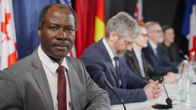 Portrait of confident African American leader in formal suit posing for camera during political press conference