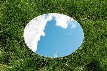 nature concept - blue sky and cloud reflection in round mirror on grass - Powered by Adobe