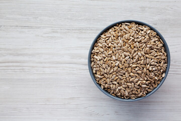 Raw Organic Sunflower Seed Kernels in a Blue Bowl on a white wooden background, top view. Flat lay, overhead, from above. Space for text.