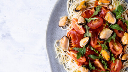Italian pasta with seafood tomato, top view. Mussels, tomato sauce and arugula on spaghetti, top view. Mediterranean style food.